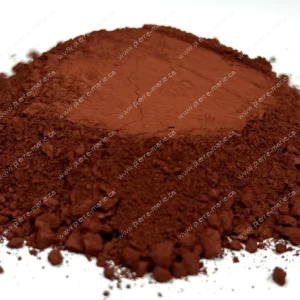 Pile of reddish-brown cocoa powder on a white surface, with loose bits around the base.